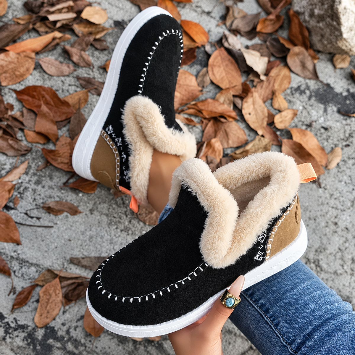 Black slip-on held up from above, showing snowflake embroidery, tan heel panel and orange pull tab 7