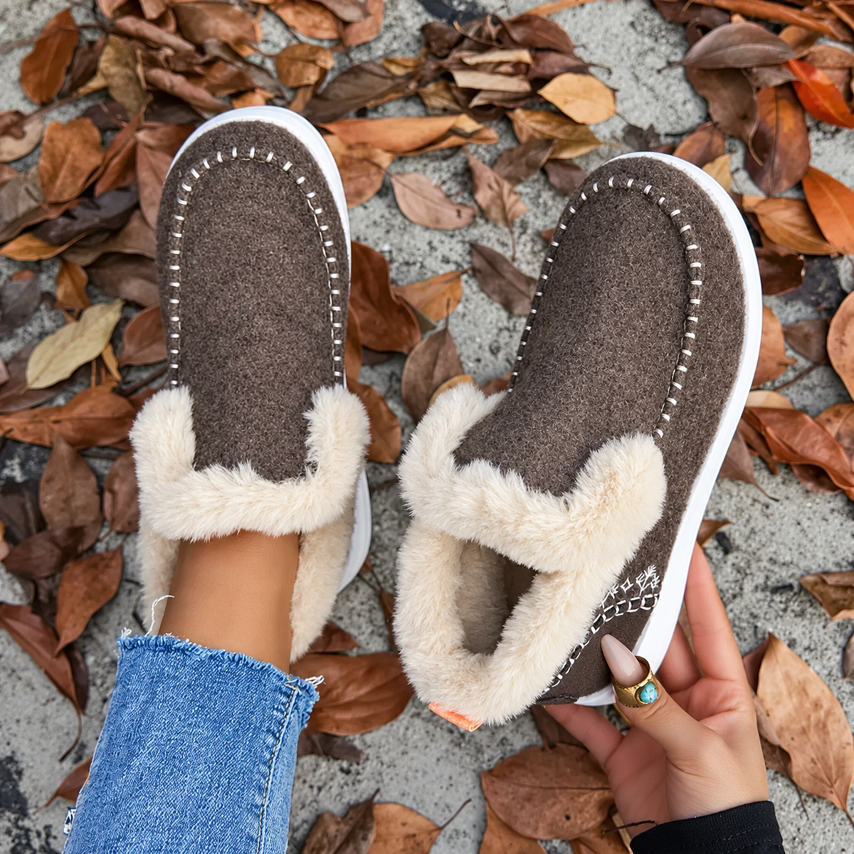 Overhead view of brown slip-ons, one on foot and one held to show the plush inner 8