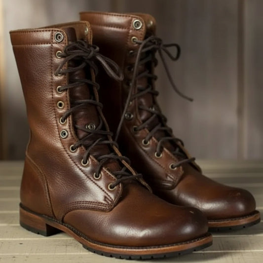 Pair of brown leather lace-up boots with dark laces and metal eyelets, standing side by side on a pale wooden surface. 1