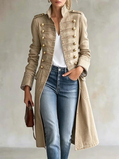Model wearing the coat in a sand-coloured version with gold buttons and tonal braiding, styled with a white top and jeans. 8