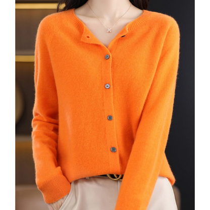 Bright orange cardigan on a model, round neck slightly open, grey buttons down the front and a belt visible at the waist. 8