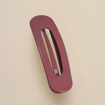 Matte burgundy-rose flat clip with a long oval opening, photographed from above on a neutral surface 13