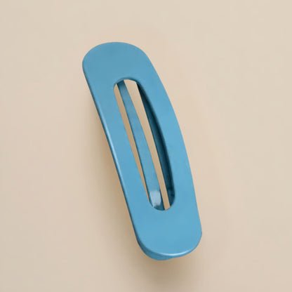 Matte steel blue flat clip with an elongated oval opening, shown from above on a beige backdrop 14