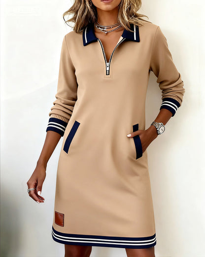Beige dress from the front on a model, hand in pocket, showing striped ribbed cuffs and hem. 9