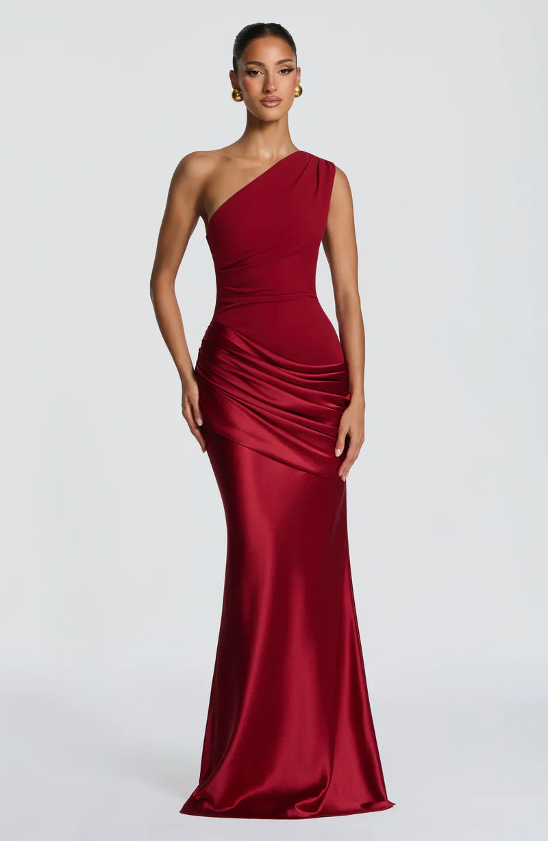 Model facing forward in the deep red one-shoulder maxi dress with ruched satin hip drape and fitted bodice, hands by her sides. 21