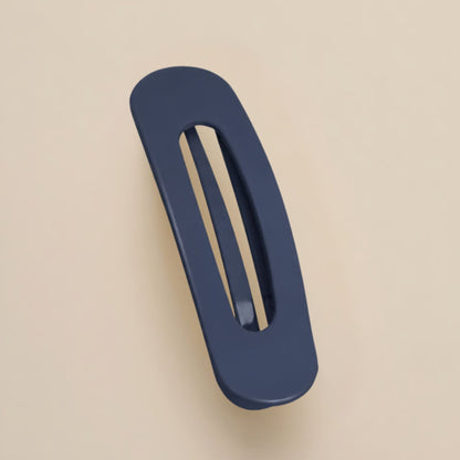 Matte navy flat clip with a long oval cut-out, photographed from above on a cream background 15
