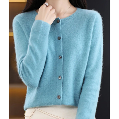 Light blue cardigan worn buttoned up with a round neckline, model's hand at her collar, ribbed cuffs and fluffy knit visible. 4