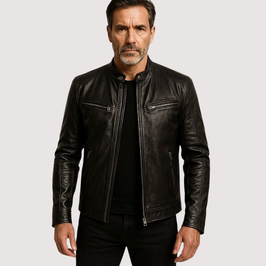 Grey-bearded man wearing the black leather biker jacket open over a black top and jeans 1