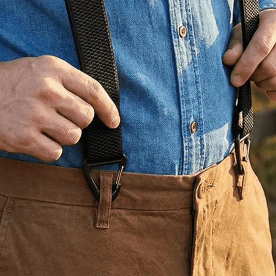 Close-up of hands holding a black brace strap with its clip fastened to tan trousers' waistband 17
