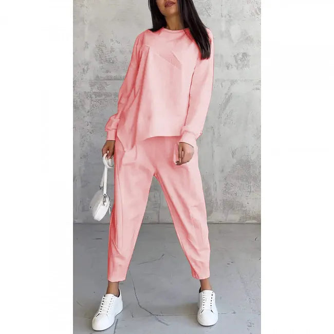 Model wearing the pale coral pink set, front view, carrying a small white bag, shown on a plain white background. 7