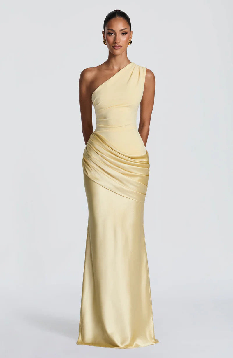 Model facing forward in the pale yellow one-shoulder satin maxi dress with ruched hip drape and softly flared skirt. 25