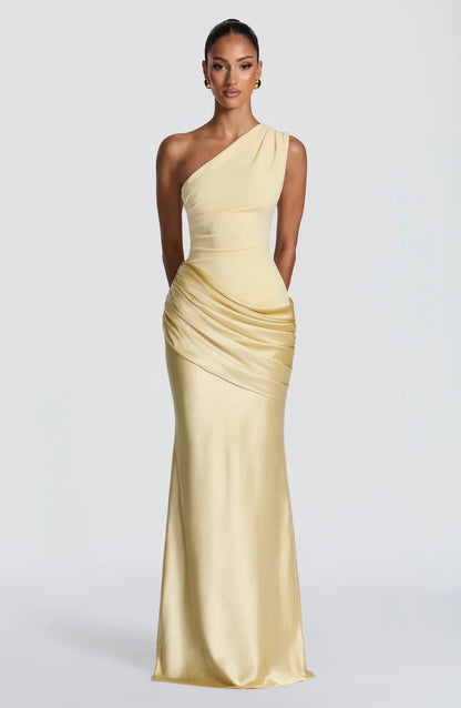 Model facing forward in the pale yellow one-shoulder satin maxi dress with ruched hip drape and softly flared skirt. 25