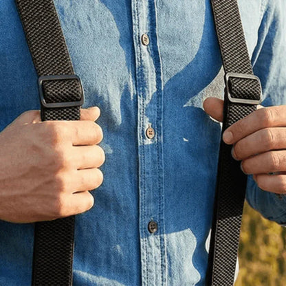Close-up of a man's hands holding black woven brace straps with metal slide adjusters over a denim shirt 18