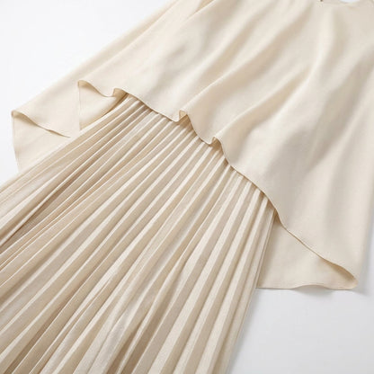 Flat lay detail of the cream cape top draped over the fine pleated skirt 4