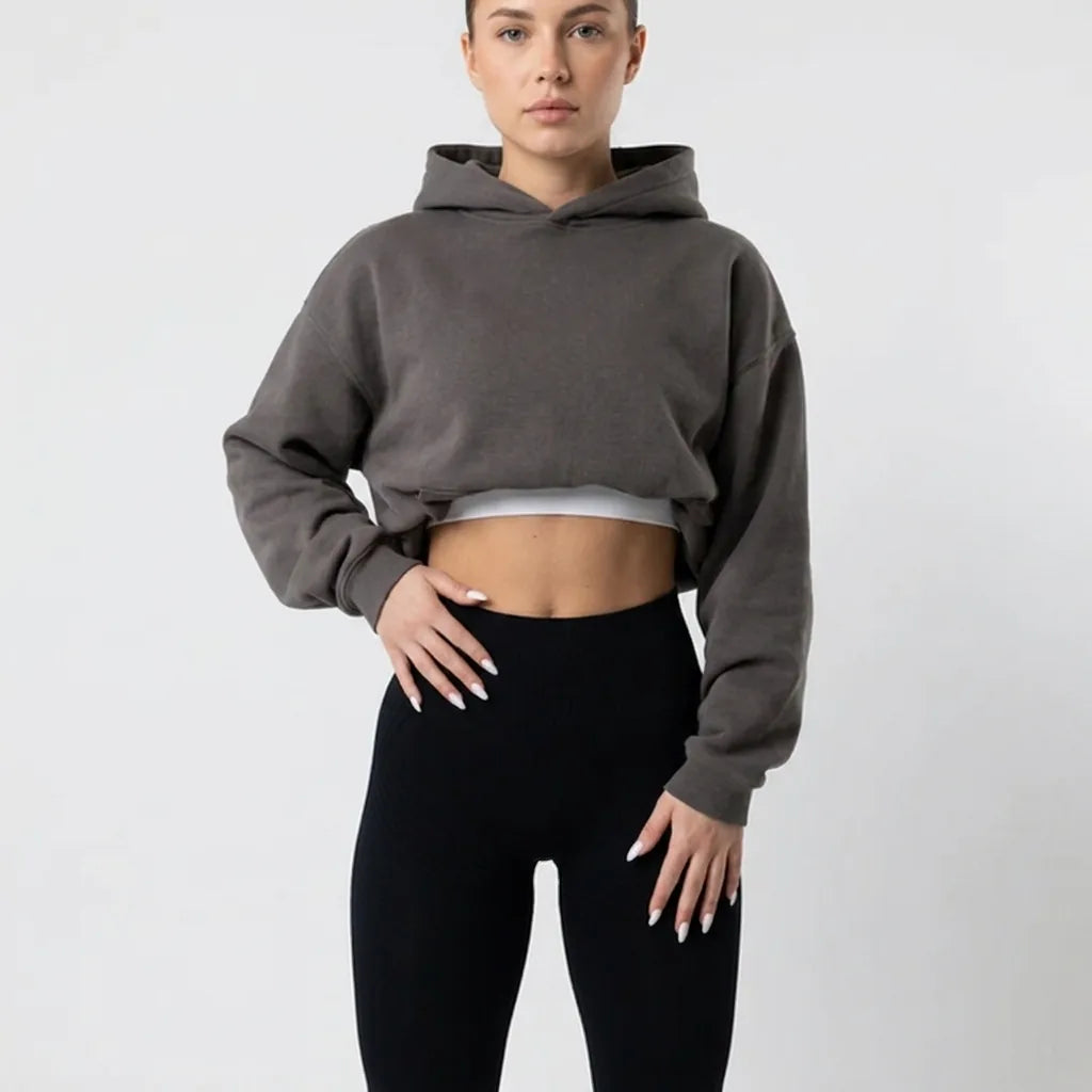 Close crop of black leggings at the waist, worn with a grey cropped hoodie over a white top. 6