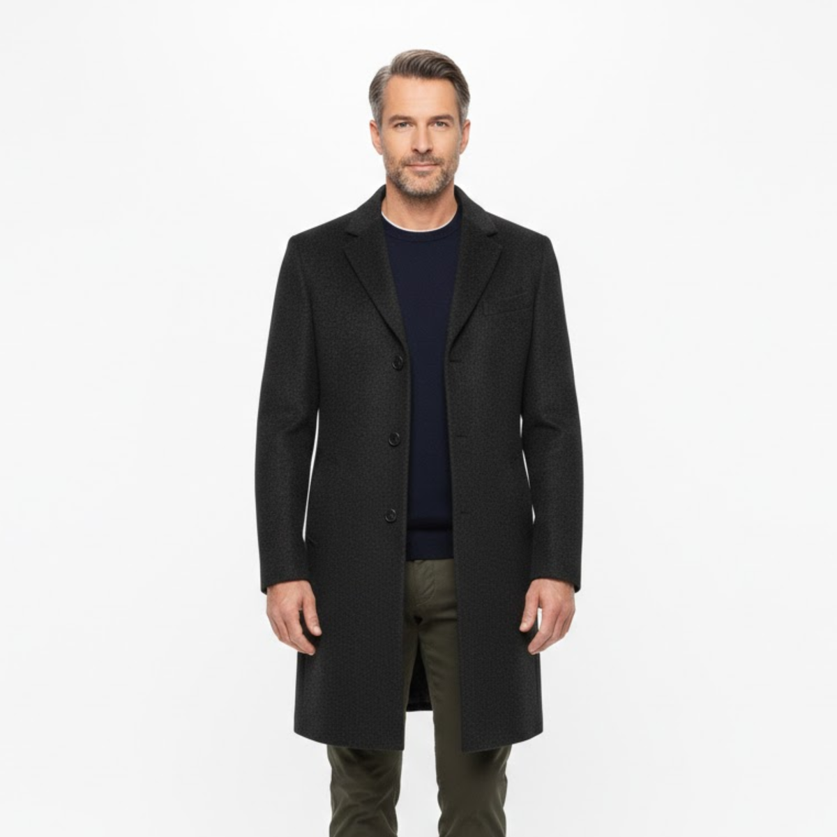 Man modelling the dark coat open over a navy jumper and olive trousers, seen from the front 2