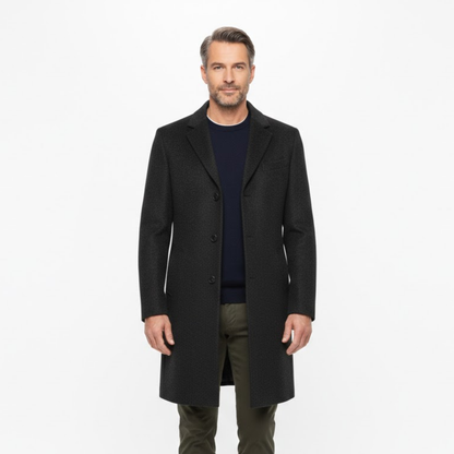 Man modelling the dark coat open over a navy jumper and olive trousers, seen from the front 2