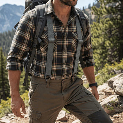 Hiker in a checked flannel shirt and khaki trousers wearing grey braces under a rucksack outdoors 13
