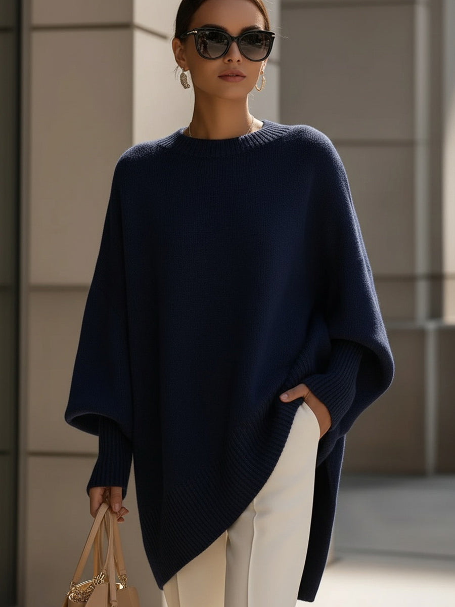 Navy blue version of the knit poncho styled with cream trousers and a tan handbag 9