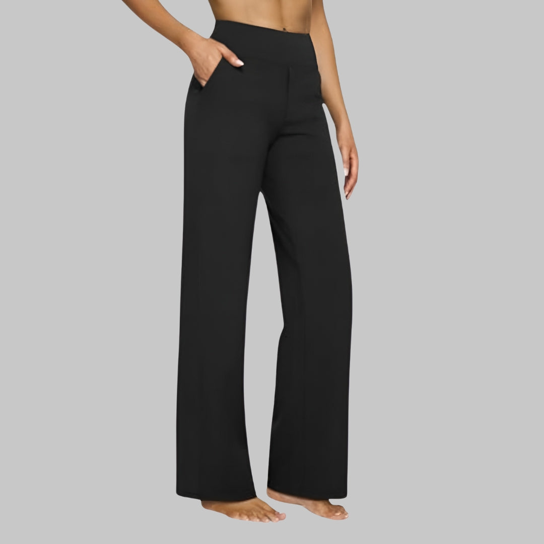 Side view of the high-waist straight-leg trousers in black, worn by a barefoot model with a hand in the side pocket. 9
