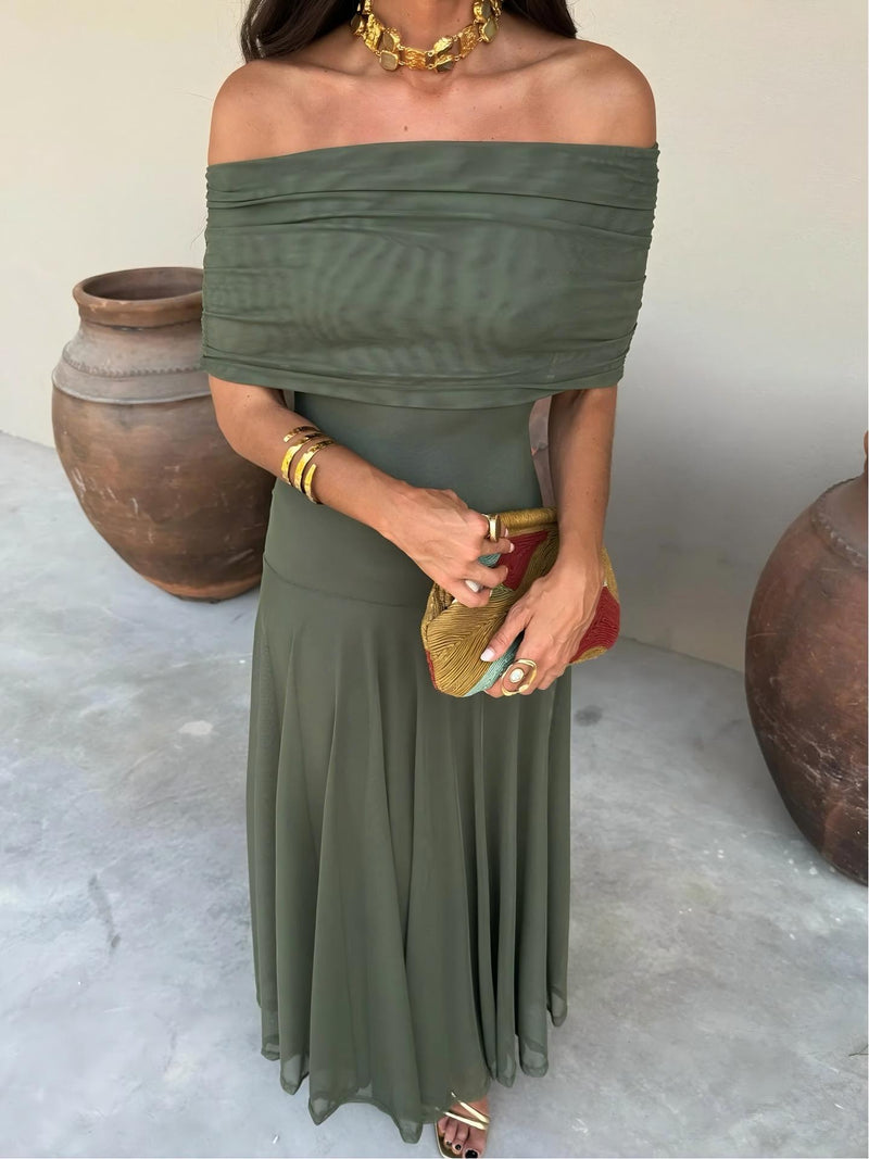 Close-up of olive green dress's ruched off-the-shoulder bodice, with gold jewellery and a colourful clutch 3