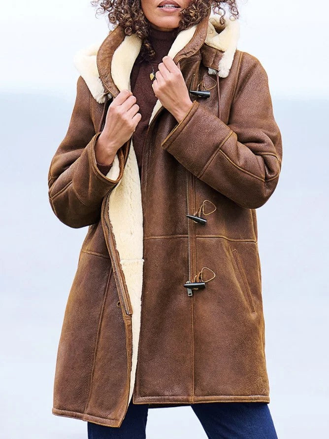 Woman wearing the brown coat open at the front, holding the collar to show the cream fleece lining and toggle fastenings. 1