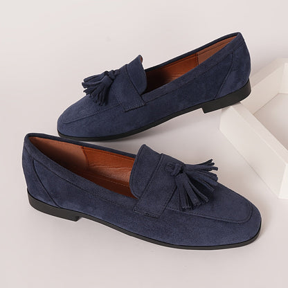 Pair of navy tasselled loafers with tan lining resting on a white block 6