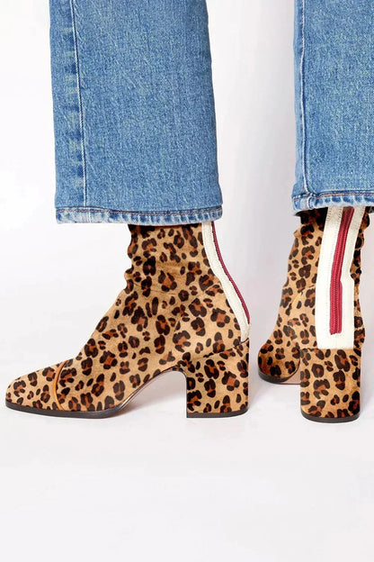 Leopard-print suede ankle boots with a block heel and cream back panel with a red zip, worn with blue jeans. 4