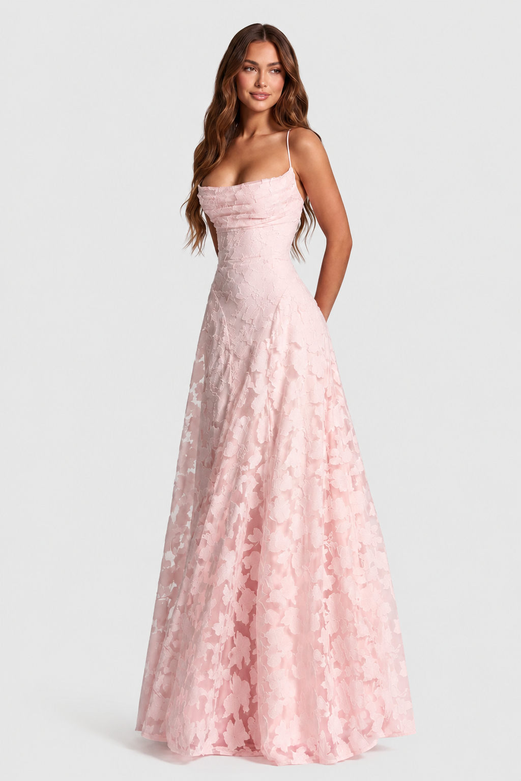 Pale pink raised floral lace gown with ruched cowl neckline and thin straps, model glancing aside in a three-quarter pose. 18