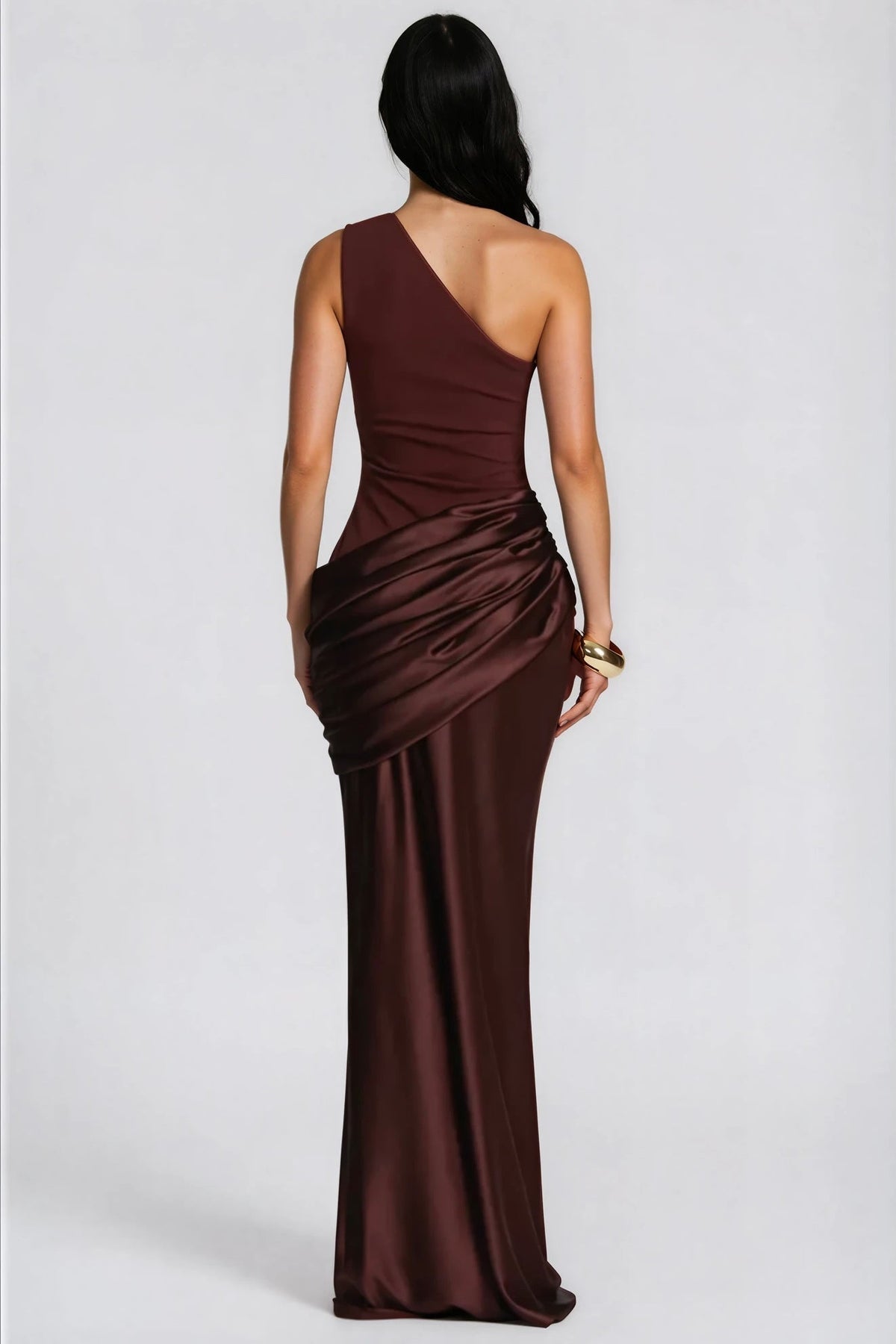 Back view of the brown gown with asymmetric strap, draped hip and a gold cuff bracelet 7