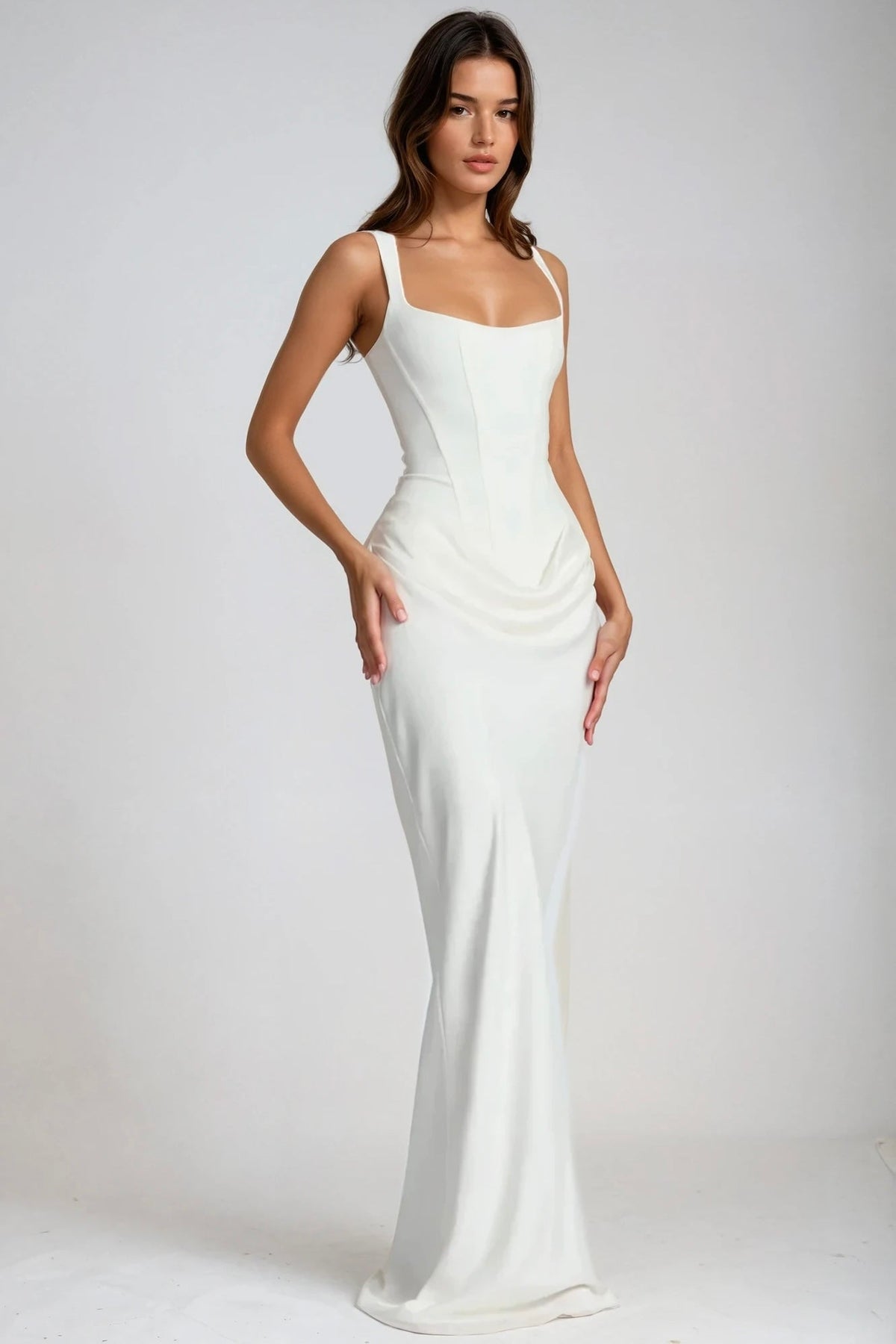 White maxi dress worn at a three-quarter angle, showing the corset seams and draped ruching at the hip 2