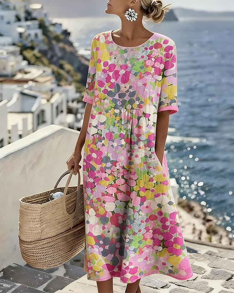 Model in the pink floral midi dress with a hand in the pocket, holding a woven basket by the sea 1