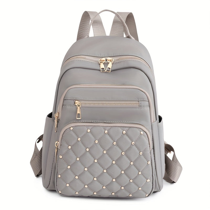 Light grey backpack front view with a quilted, gold-studded front pocket and gold zips 14