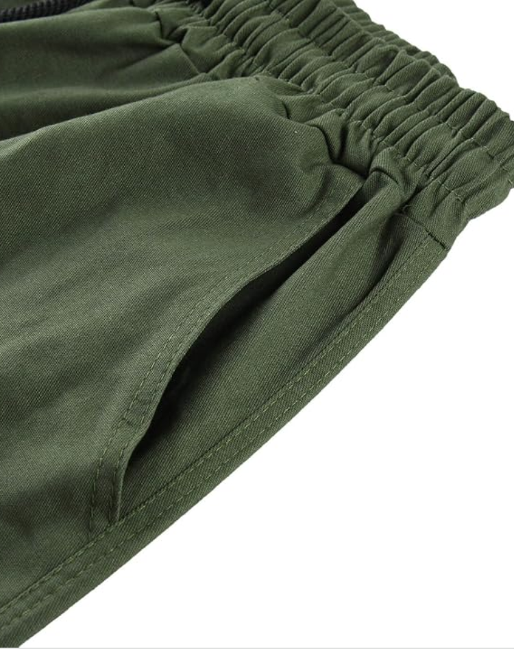 Close-up of the olive green elasticated waistband and the stitched side pocket opening on the trousers. 13