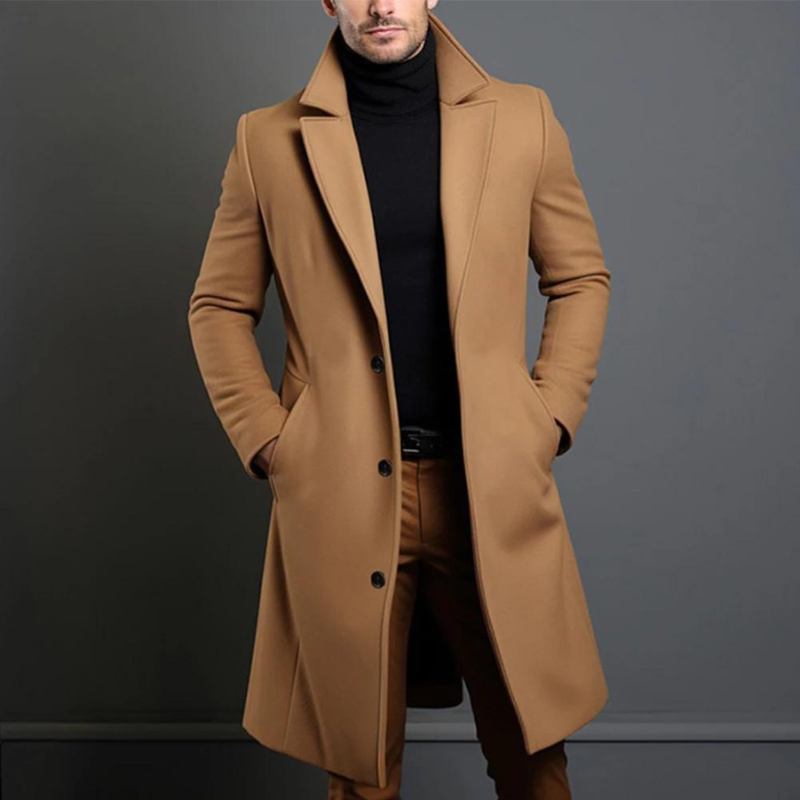 Model wearing the camel version of the longline coat, buttoned at the front, with a black roll-neck and tan trousers. 2