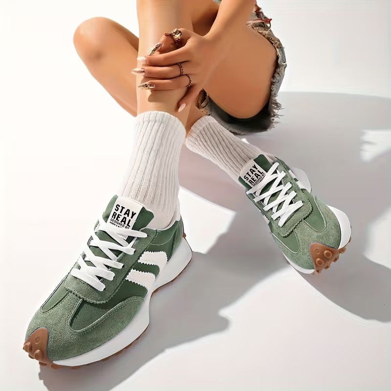 Model sitting with legs crossed, wearing green suede trainers with white ribbed socks and denim shorts 7