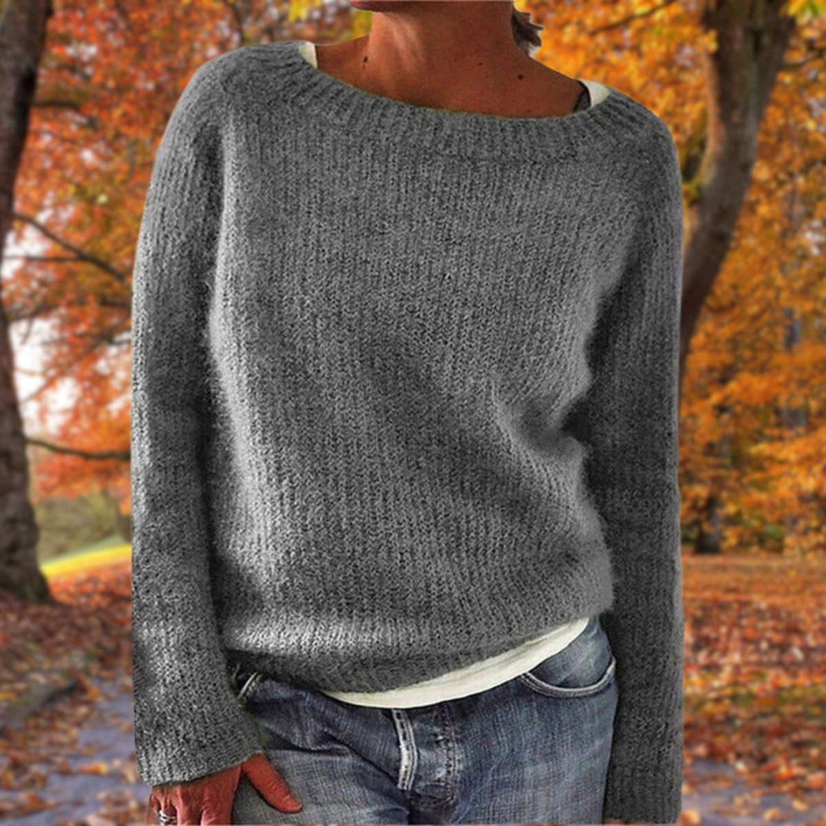 Grey knit sweater with a wide neckline, worn over a white top with jeans against autumn foliage 4