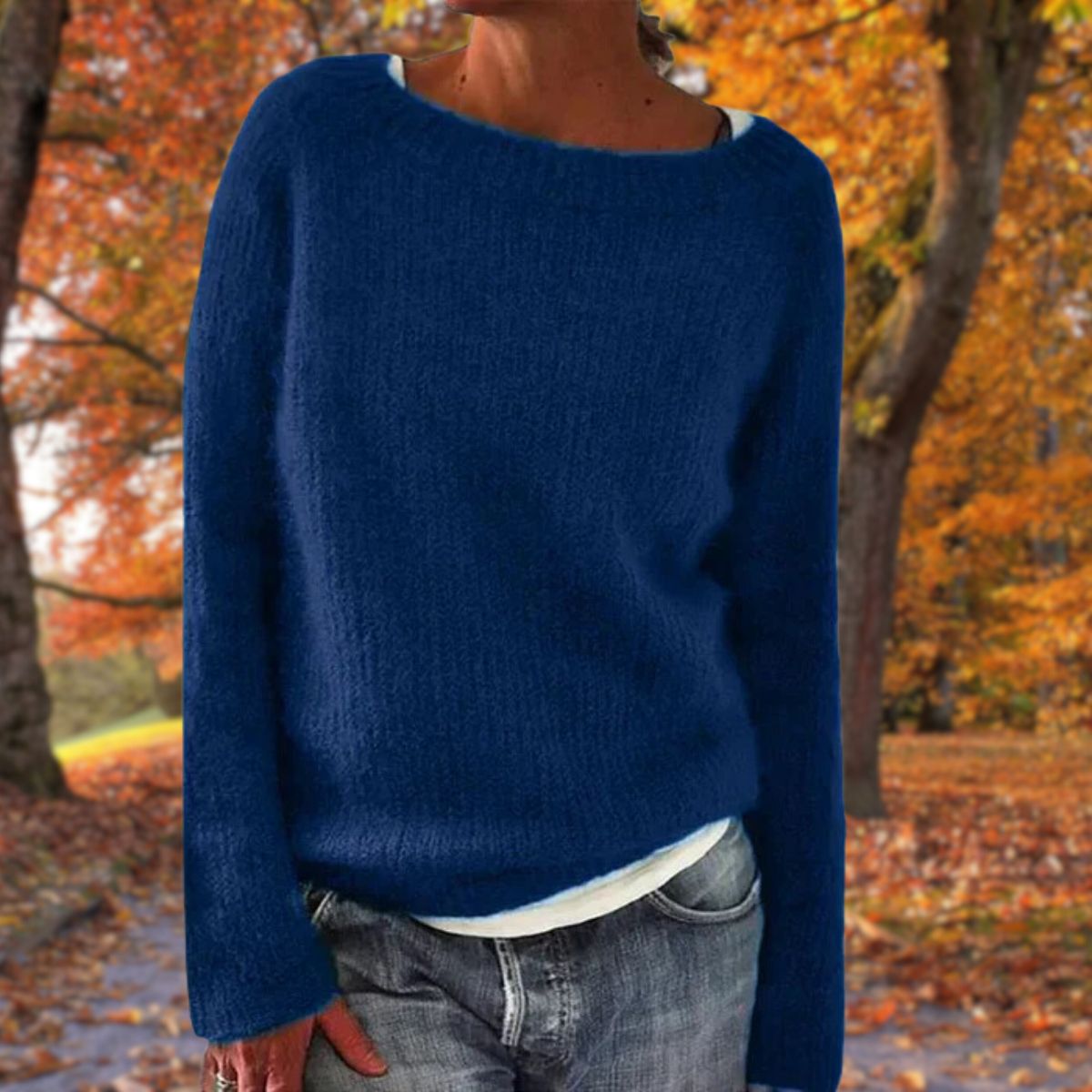 Navy blue knit sweater with a wide neckline, worn over a white top and jeans in an autumn park 3