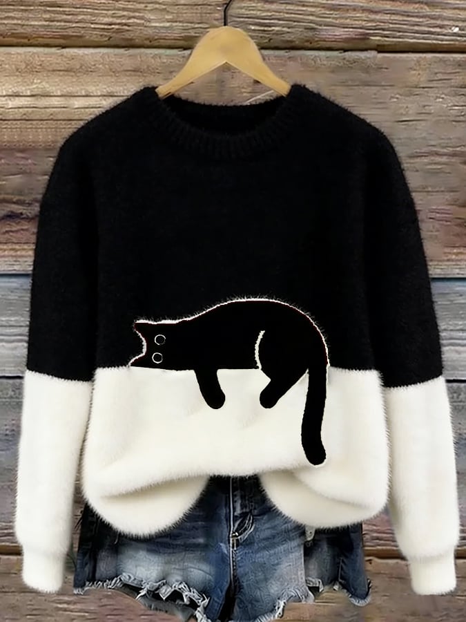 Black and white fluffy jumper with black cat motif, hanging on a wooden background 6