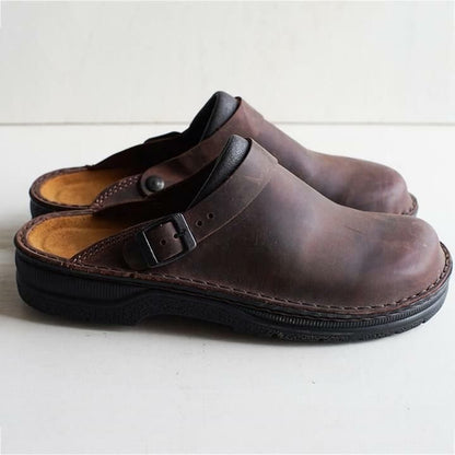 Side view of a pair of dark brown leather clogs with buckle strap and thick black sole 4