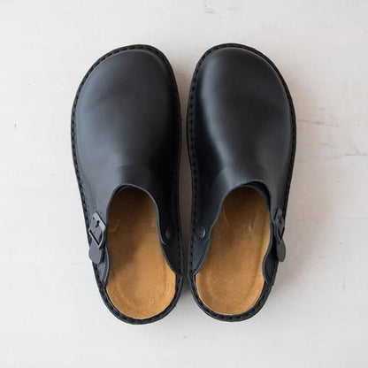 Top-down view of black leather clogs showing the tan cushioned footbeds and side buckles 9