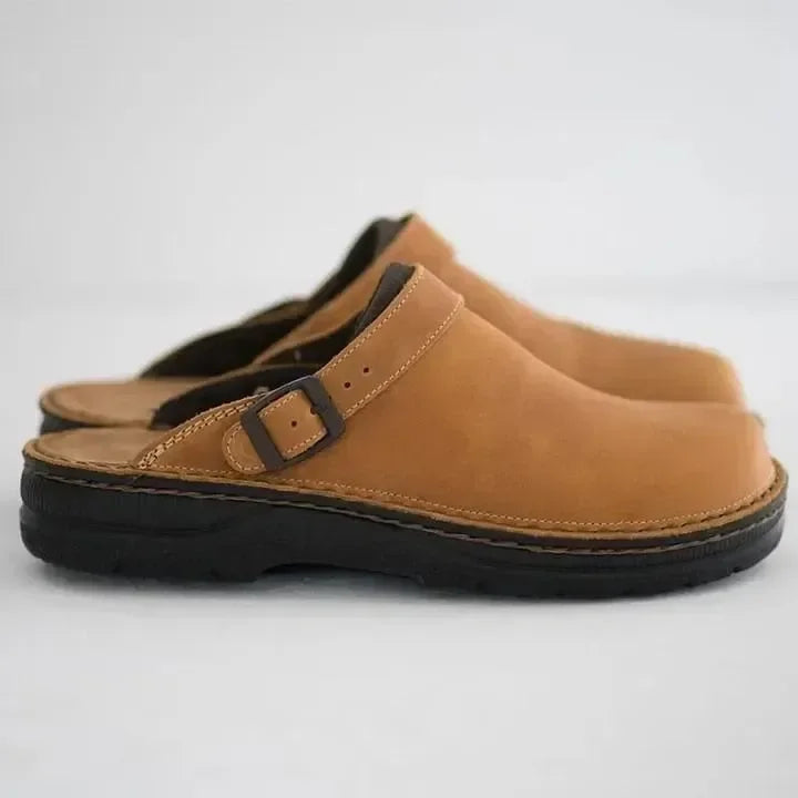 Side view of a pair of light tan nubuck clogs with contrast stitching and buckle strap 5