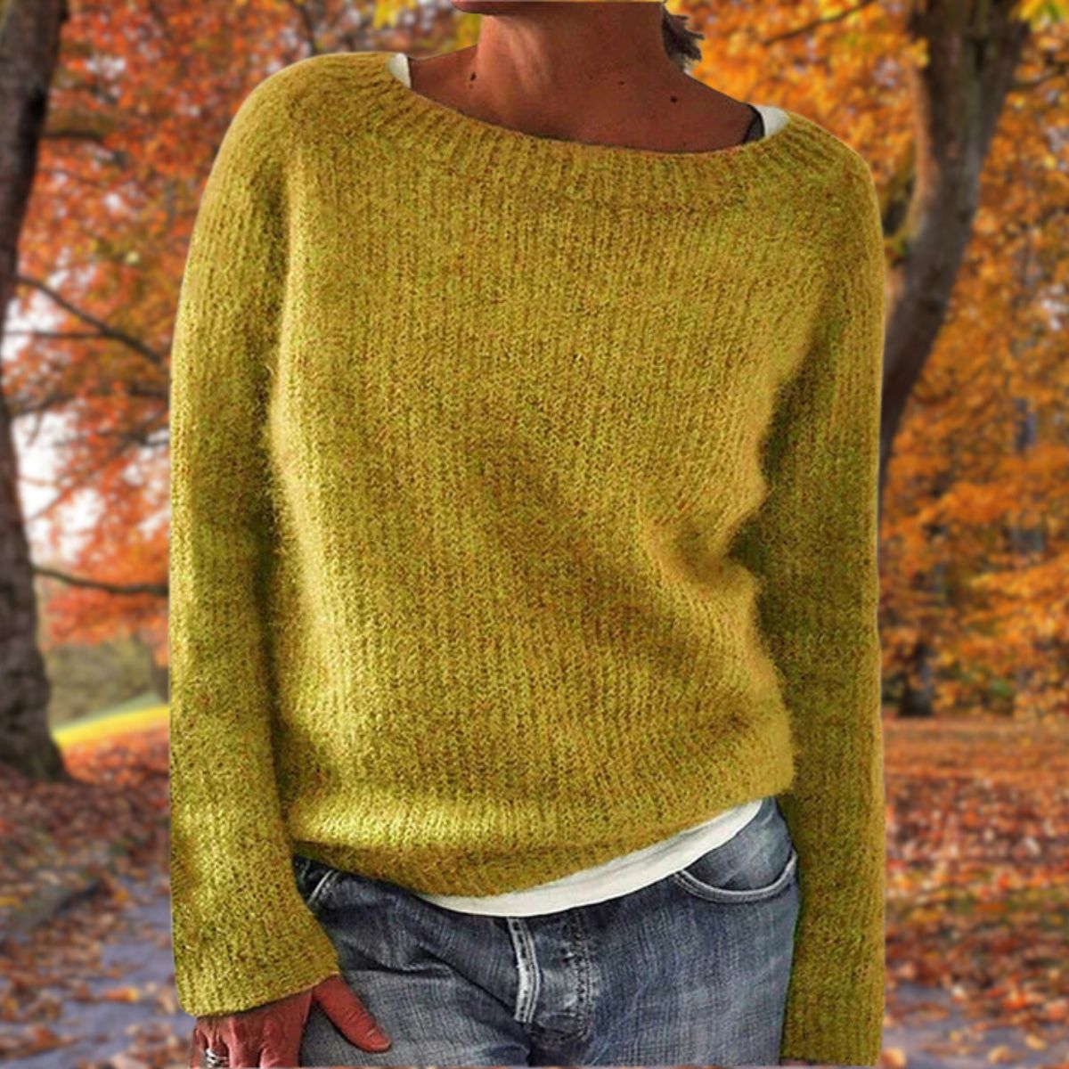 Mustard yellow knit sweater with a wide neckline, worn over a white top and jeans among autumn trees 1