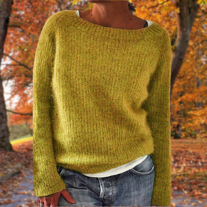 Mustard yellow knit sweater with a wide neckline, worn over a white top and jeans among autumn trees 1
