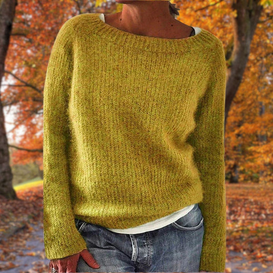 Mustard yellow knit sweater with a wide neckline, worn over a white top and jeans among autumn trees 1