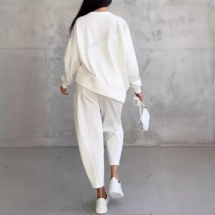Back view of the white set on a model walking away, showing the loose sweatshirt, tapered trousers and white trainers. 9