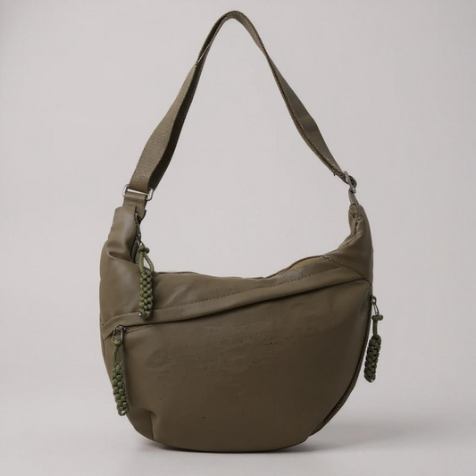Crescent-shaped olive green bag with a single top strap and braided zip pulls, shown on a plain grey background. 1