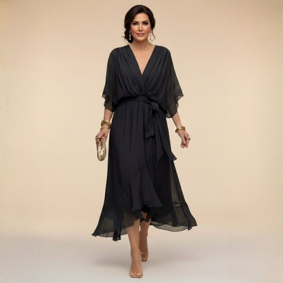 Model walking in the black chiffon midi dress with draped V-neck, wide flowing sleeves, tied waist sash and ruffled asymmetric hem. 2