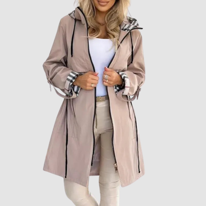 Model in the pale taupe version of the long hooded coat, worn open with checked cuffs turned back and cream trousers. 2