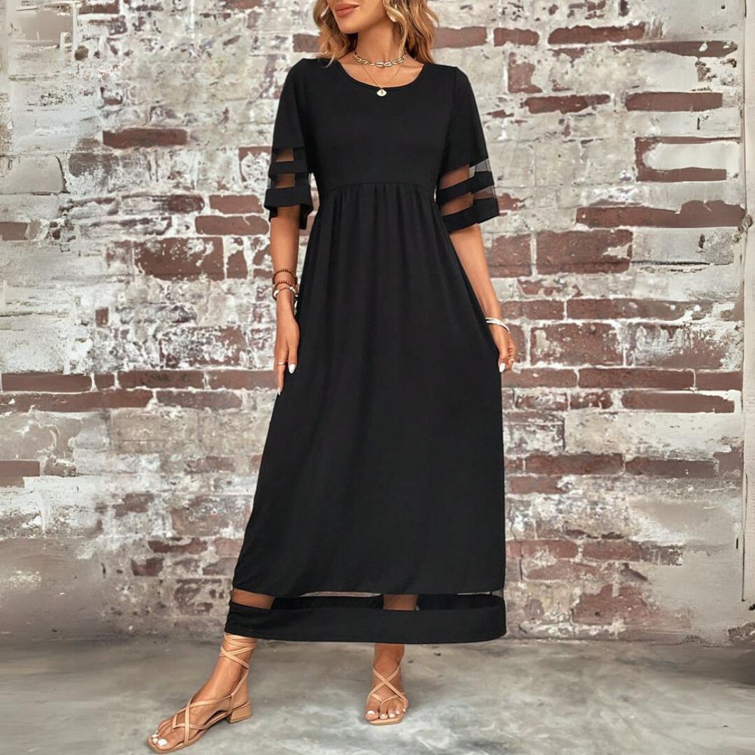 Three-quarter front view of the black dress with round neckline, sheer sleeve stripes and mesh hem band, against a brick wall. 4